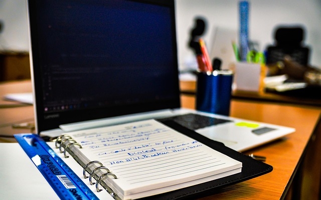 Afbeelding van een computer met een papieren notitieboek erop